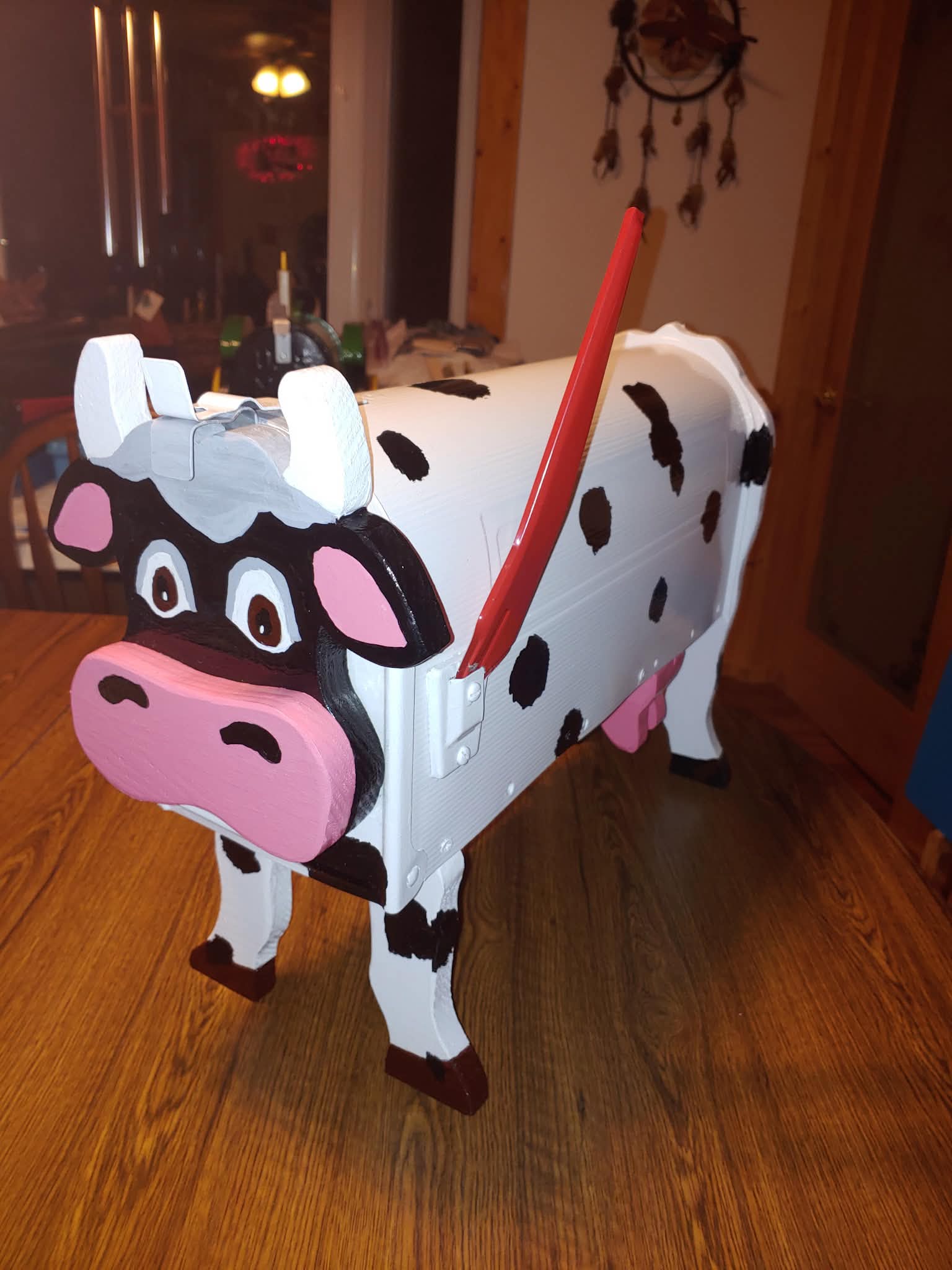 Custom wooden mailbox shaped and painted like a spotted black-and-white dairy cow