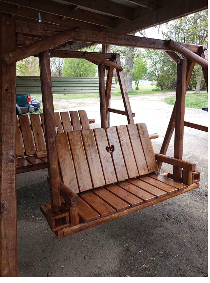 Dark stained swing with carved heart under covered A-frame